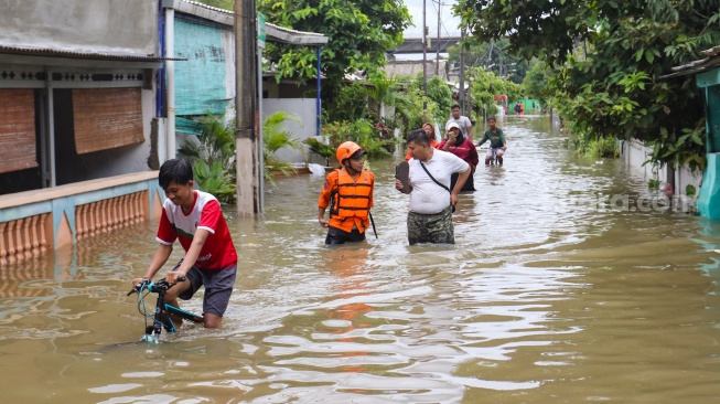 Warga beraktivitas di tengah banjir yang terjadi di pemukiman, kawasan Cakung, Jakarta, Rabu (29/1/2025). [Suara.com/Alfian Winanto]