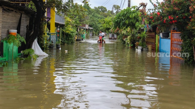 Warga beraktivitas di tengah banjir yang terjadi di pemukiman, kawasan Cakung, Jakarta, Rabu (29/1/2025). [Suara.com/Alfian Winanto]