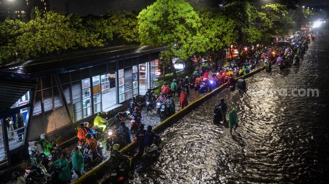 Sejumlah pengendara motor menuntun motornya melewati banjir di Jalan Daan Mogot, Cengkareng, Jakarta, Selasa (28/1/2025). [ANTARA FOTO/Putra M. Akbar/gp/foc]