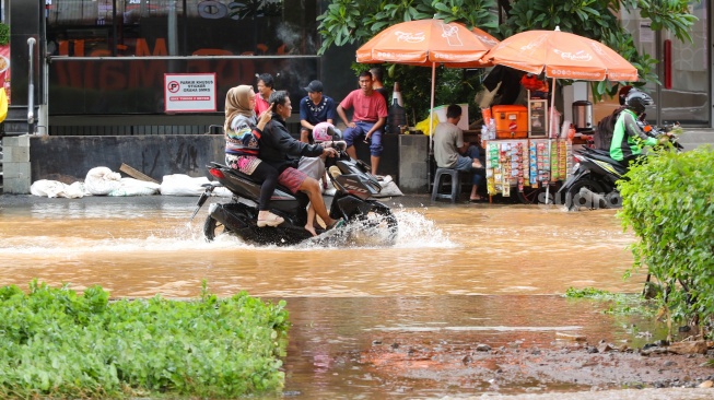 Pengendara melintasi banjir di Jalan Boulevard Raya, Kelapa Gading, Jakarta, Rabu (29/1/2025). [Suara.com/Alfian Winanto]