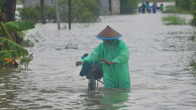 Warga berjalan menerobos jalan yang tergenang banjir di Dukuh Karangturi, Desa Setrokalangan, Kaliwungu, Kudus, Jawa Tengah, Jumat (31/1/2025). [ANTARA FOTO/Ahmad Subaidi/nz]