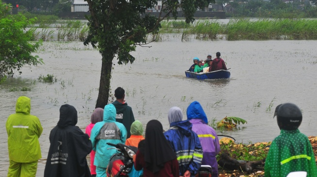 Warga menunggu kedatangan perahu untuk melintasi jalan yang tergenang banjir di Dukuh Karangturi, Desa Setrokalangan, Kaliwungu, Kudus, Jawa Tengah, Jumat (31/1/2025). [ANTARA FOTO/Yusuf Nugroho/foc]