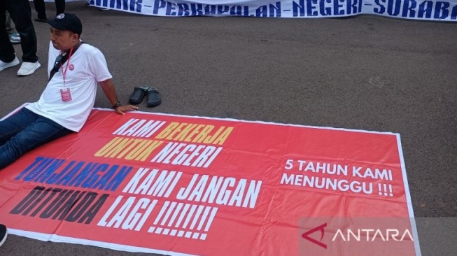 Peserta aksi demo saat duduk di antara sepanduk yang dibawa dalam aksi di depan Patung Kuda, Jakarta, Senin (3/2/2025). ANTARA/Khaerul Izan