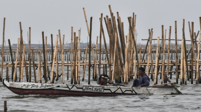 Nelayan melintas di samping pagar laut saat aksi protes di pesisir Tarumajaya, Desa Segarajaya, Kabupaten Bekasi, Selasa (4/2/2025). [ANTARA FOTO/Fakhri Hermansyah/YU]