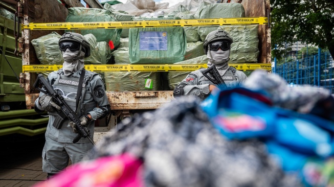 Petugas Badan Keamanan Laut (Bakamla) berjaga di depan barang bukti truk membawa pakaian bekas saat ekspose hasil pengawasan oleh Kementerian Perdagangan dan Bakamla di Jakarta, Rabu (5/2/2025). [ANTARA FOTO/Bayu Pratama S/rwa]