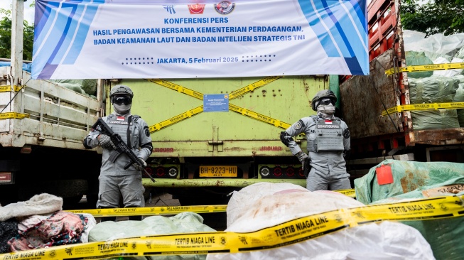 Petugas Badan Keamanan Laut (Bakamla) berjaga di depan barang bukti truk membawa pakaian bekas saat ekspose hasil pengawasan oleh Kementerian Perdagangan dan Bakamla di Jakarta, Rabu (5/2/2025). [ANTARA FOTO/Bayu Pratama S/rwa]