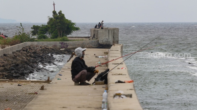 Warga beraktivitas di sekitar tanggul laut kawasan muara baru, Jakarta, Rabu (5/2/2025). [Suara.com/Alfian Winanto]