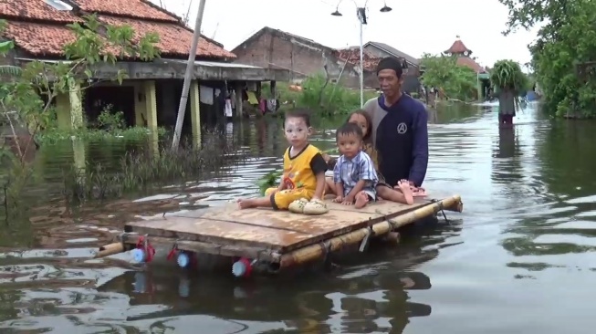 Warga Desa Sayung, Kecamatan Sayung, Kabupaten Demak, menggunakan rakit buatan untuk aktivitas di luar rumah, Jumat (7/2/2025). (suara.com/Sigit AF)