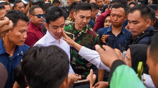 Wakil Presiden Gibran Rakabuming Raka (ketiga kiri) wajahnya dipegang warga saat membagikan alat tulis kepada warga seusai meninjau proyek terowongan di Jalan Sultan Alimudin di Samarinda, Kalimantan Timur, Rabu (12/2/2025). [ANTARA FOTO/M Risyal Hidayat/nym]