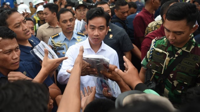 Wakil Presiden Gibran Rakabuming Raka (tengah) membagikan alat tulis kepada warga seusai meninjau proyek terowongan di Jalan Sultan Alimudin di Samarinda, Kalimantan Timur, Rabu (12/2/2025). [ANTARA FOTO/M Risyal Hidayat/nym]