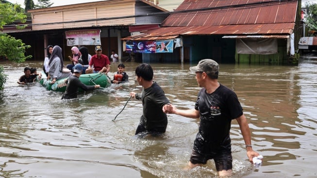 Warga melintasi banjir menggunakan perahu karet di Kelurahan Manggala, Makassar, Sulawesi Selatan, Rabu (12/2/2025). [ANTARA FOTO/Arnas Padda/foc]