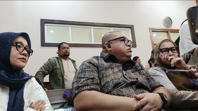 Razman Arif Nasution diapit dua istrinya, Nur Elly Rambe Heriani Rambe (jilbab cokelat) dan Ade Suryani (jilbab biru) di Pengadilan Negeri Jakarta Utara pada Kamis (20/2/2025). [Suara.com/Rena Pangesti]