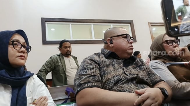 Razman Arif Nasution diapit dua istrinya, Nur Elly Rambe Heriani Rambe (jilbab cokelat) dan Ade Suryani (jilbab biru) di Pengadilan Negeri Jakarta Utara pada Kamis (20/2/2025). [Suara.com/Rena Pangesti]