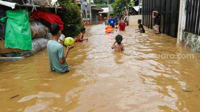 Warga beraktivitas di tengah banjir yang melanda di kawasan Tanjung Sanyang, Cawang, Jakarta, Senin (3/3/2025). [Suara.com/Alfian Winanto]
