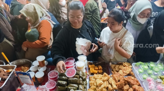 Warga berdesakan untuk membeli makanan yang dijual di Bazar Takjil, Bendungan Hilir, Jakarta, Senin (3/3/2025). [Suara.com/Alfian Winanto]
