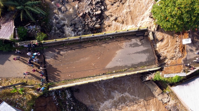Foto udara kondisi jembatan Ciliwung yang putus akibat meluapnya sungai Ciliwung di Desa Jogjogan, Cisarua, Kabupaten Bogor, Jawa Barat, Senin (3/3/2025). [ANTARA FOTO/Yulius Satria Wijaya/YU]