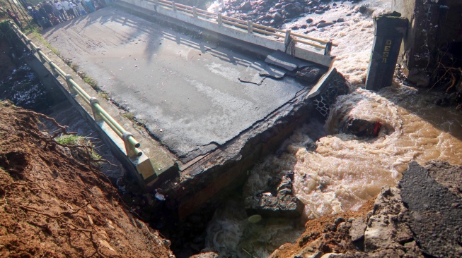 Warga melihat kondisi jembatan Ciliwung yang putus akibat meluapnya sungai Ciliwung di Desa Jogjogan, Cisarua, Kabupaten Bogor, Jawa Barat, Senin (3/3/2025). [ANTARA FOTO/Yulius Satria Wijaya/YU]