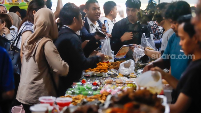 Warga berdesakan untuk membeli makanan yang dijual di Bazar Takjil, Bendungan Hilir, Jakarta, Senin (3/3/2025). [Suara.com/Alfian Winanto]