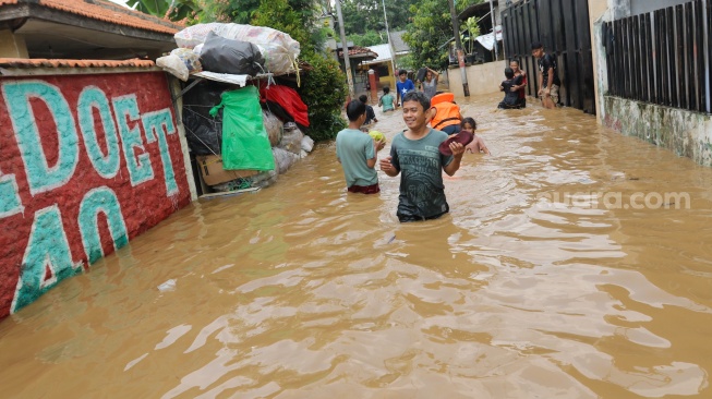 Warga beraktivitas di tengah banjir yang melanda di kawasan Tanjung Sanyang, Cawang, Jakarta, Senin (3/3/2025). [Suara.com/Alfian Winanto]
