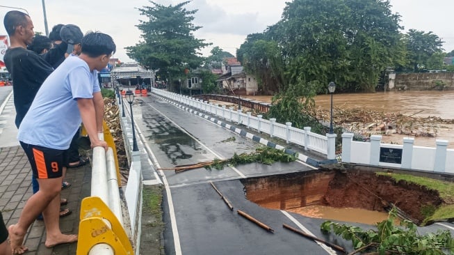 Warga melihat jembatan yang amblas di kawasan perumahan Kemang Pratama, Bekasi, Jawa Barat, Selasa (4/3/2025). [Suara.com/Alfian Winanto]