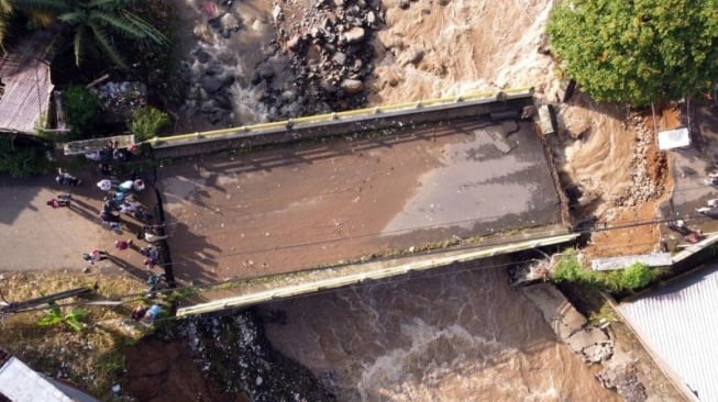 Foto udara kondisi jembatan Ciliwung yang putus akibat meluapnya sungai Ciliwung di Desa Jogjogan, Cisarua, Kabupaten Bogor, Jawa Barat. (ANTARA FOTO/Yulius Satria Wijaya/foc.)