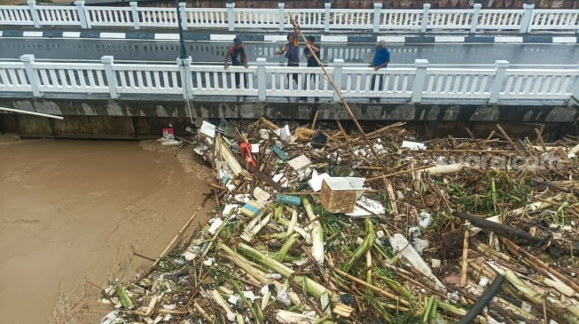 Kondisi jembatan yang dipenuhi sampah kiriman di kawasan perumahan Kemang Pratama, Bekasi, Jawa Barat, Selasa (4/3/2025). [Suara.com/Alfian Winanto]