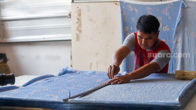 Pekerja memotong bahan untuk dijadikan mukena di Pondok Aren, Tangerang Selatan, Rabu (5/3/2025). [Suara.com/Alfian Winanto]