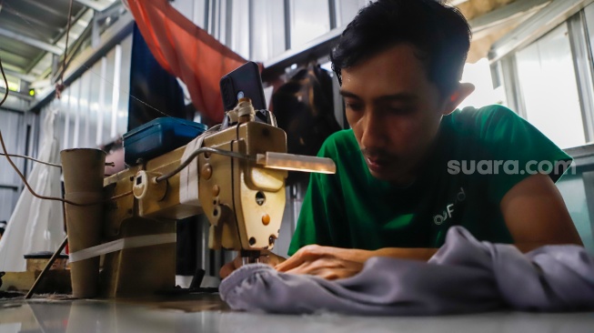 Pekerja menjahit bahan untuk dijadikan mukena di Pondok Aren, Tangerang Selatan, Rabu (5/3/2025). [Suara.com/Alfian Winanto]