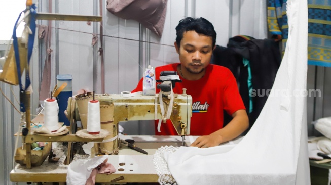 Pekerja menjahit bahan untuk dijadikan mukena di Pondok Aren, Tangerang Selatan, Rabu (5/3/2025). [Suara.com/Alfian Winanto]