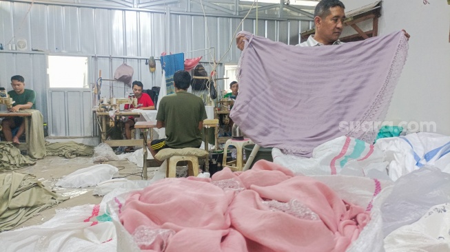 Pekerja menjahit bahan untuk dijadikan mukena di Pondok Aren, Tangerang Selatan, Rabu (5/3/2025). [Suara.com/Alfian Winanto]