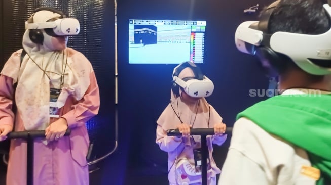 Pengunjung menggunakan perangkat virtual reality (VR) saat simulasi manasik haji di arena Manasik Xperience, Kuningan City, Jakarta, Senin (10/3/2025). [Suara.com/Alfian Winanto]