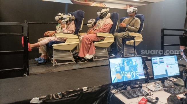 Pengunjung menggunakan perangkat virtual reality (VR) saat simulasi manasik haji di arena Manasik Xperience, Kuningan City, Jakarta, Senin (10/3/2025). [Suara.com/Alfian Winanto]