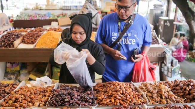 Pembeli memilih buah kurma di Pasar Tanah Abang, Jakarta, Rabu (12/3/2025). [Suara.com/Alfian Winanto]