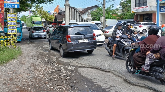 Spanduk tulisan " Selamat Datang di Wisata Jeglongan Sewu' terpasang di Jalan Raya Solo-Baki yang kondisinya rusak. [Suara.com/Ari Welianto]