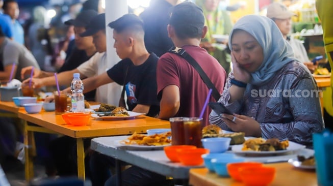 Pengunjung menunggu waktu berbuka puasa di Sentra kuliner Nasi Kapau di Jalan Kramat Raya, Senen, Jakarta, Selasa (18/3/2025). [Suara.com/Alfian Winanto]
