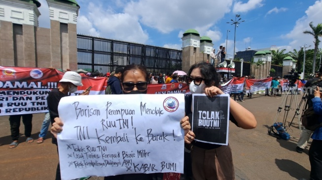 Salut! Dua Wanita Ini Tetap Berdiri Bawa Poster Penolakan di Tengah Massa Pendukung RUU TNI