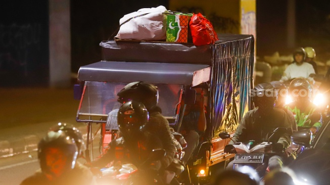 Pemudik melintas di Jalan Inspeksi Kalimalang, Bekasi, Jawa Barat, Jumat (28/3/2025). [Suara.com/Alfian Winanto]