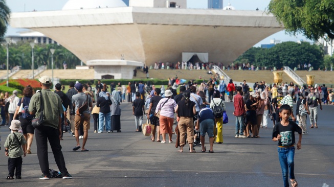 Warga berswafoto saat berwisata di Monumen Nasional (Monas), Jakarta, Sabtu (5/4/2025). [Suara.com/Alfian Winanto]