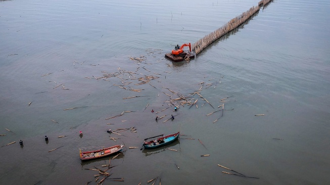 Foto udara pekerja menggunakan alat berat saat membongkar pagar laut di pesisir laut Desa Kohod, Kabupaten Tangerang, Banten, Kamis (17/4/2025). [ANTARA FOTO/Putra M. Akbar/nym]