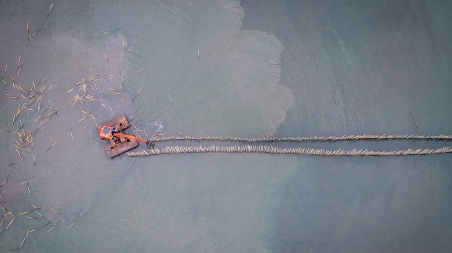 Foto udara pekerja menggunakan alat berat saat membongkar pagar laut di pesisir laut Desa Kohod, Kabupaten Tangerang, Banten, Kamis (17/4/2025). [ANTARA FOTO/Putra M. Akbar/nym]