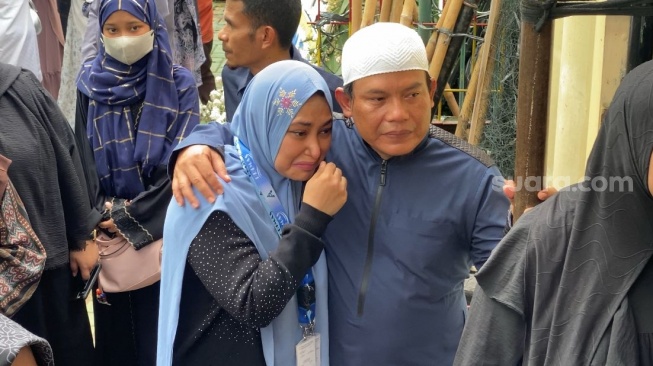 Faank Wali dan istrinya, Sari menyaksikan prosesi pemakaman sang ibu di kawasan Pondok Gede, Bekasi, Jawa Barat pada Minggu (20/4/2025). [Suara.com/Tiara Rosana]