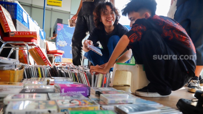 Pengunjung memilih rilisan fisik yang ditawarkan dalam acara Record Store Day Indonesia x Pop City di Senayan Park, Jakarta, Jumat (25/4/2025). [Suara.com/Alfian Winanto] 