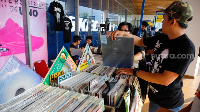 Pengunjung memilih rilisan fisik yang ditawarkan dalam acara Record Store Day Indonesia x Pop City di Senayan Park, Jakarta, Jumat (25/4/2025). [Suara.com/Alfian Winanto] 