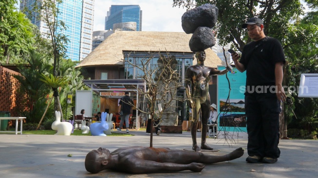 Pengunjung melihat karya instalasi seni pada Pameran Art Jakarta Gardens di Hutan Kota Plataran, Senayan, Jakarta, Jumat (25/4/2025). [Suara.com/Alfian Winanto]