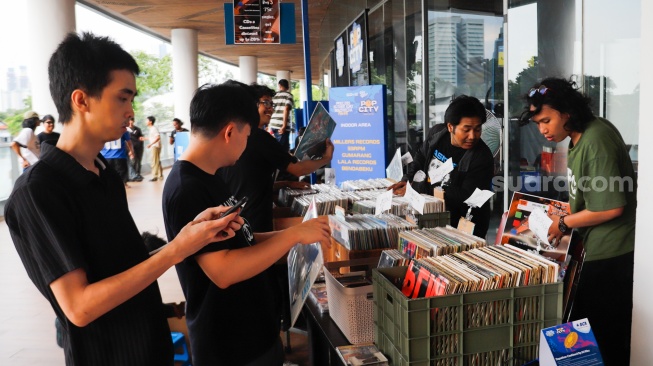 Pengunjung memilih rilisan fisik yang ditawarkan dalam acara Record Store Day Indonesia x Pop City di Senayan Park, Jakarta, Jumat (25/4/2025). [Suara.com/Alfian Winanto] 