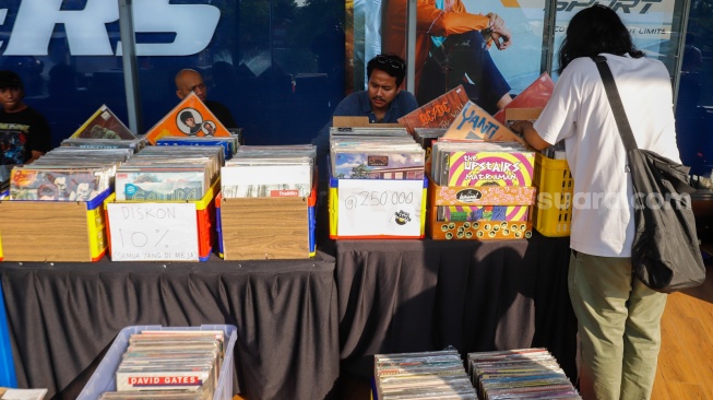 Pengunjung memilih rilisan fisik yang ditawarkan dalam acara Record Store Day Indonesia x Pop City di Senayan Park, Jakarta, Jumat (25/4/2025). [Suara.com/Alfian Winanto] 