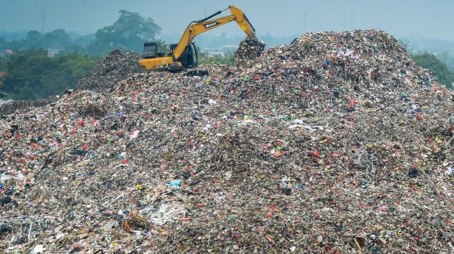 Petugas menggunakan alat berat saat mengeruk sampah di Tempat Pembuangan Akhir (TPA) Jatiwaringin, Kabupaten Tangerang, Banten, Selasa (29/4/2025). [Suara.com/Alfian Winanto]
