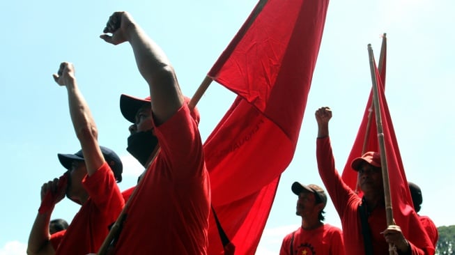 Buruh membawa bendera saat mengikuti aksi Hari Buruh Internasional di depan Gedung DPRD, Malang, Jawa Timur, Kamis (1/5/2025).  [ANTARA FOTO/Ari Bowo Sucipto/YU]