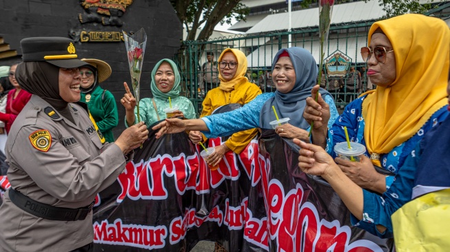 Polisi perempuan membagikan bunga mawar kepada peserta aksi pada peringatan Hari Buruh Internasional di depan Kompleks Gedung DPRD Jawa Tengah, Kota Semarang, Kamis (1/5/2025). [ANTARA FOTO/Aji Styawan/YU]
