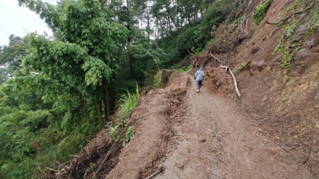 Warga melintasi jalan yang tertimbun longsor di Desa Ndikosapu, Kabupaten Ende, Nusa Tenggara Timur [SuaraSulsel.id/ANTARA]